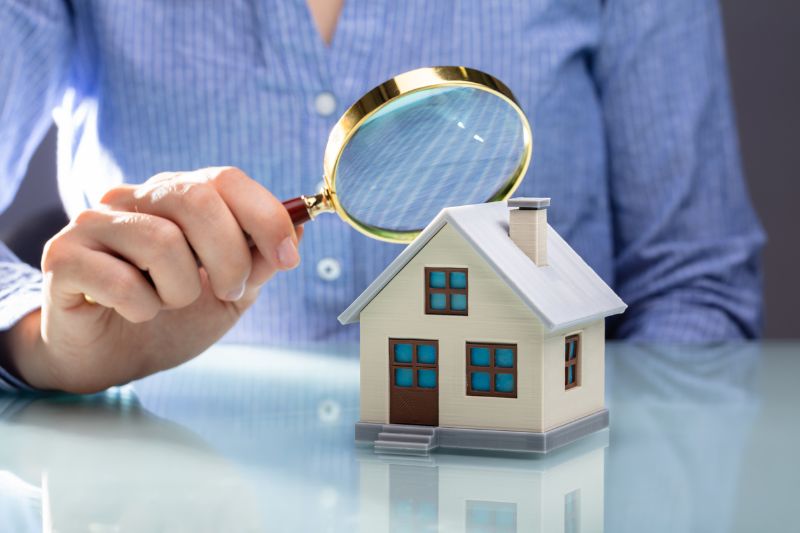 businesswoman holding magnifying glass over house model