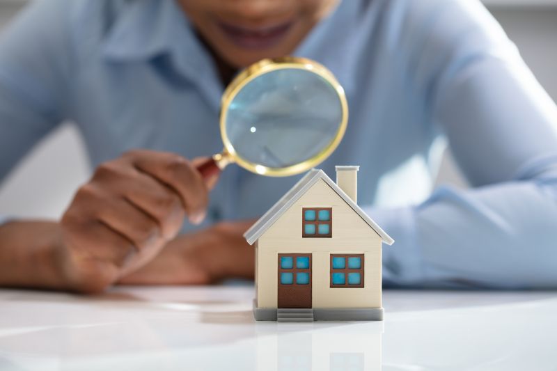 businesswoman holding magnifying glass over house model