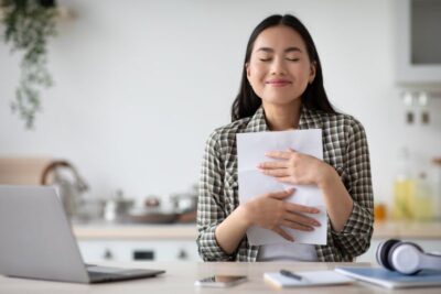 delighted young asian woman student reading invitation letter